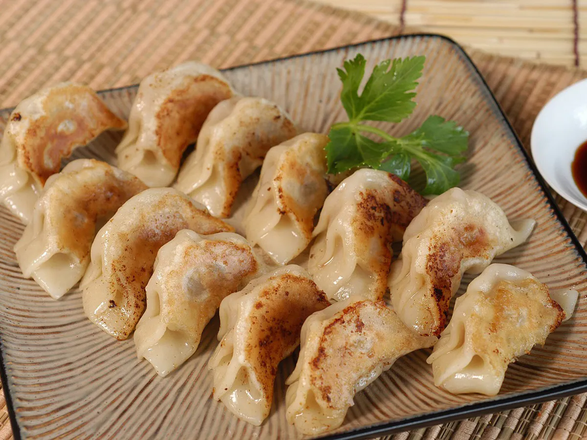 Pan fried crispy potstickers served on textured ceramic plate at JBO Kitchen, an Asian Fusion Restaurant in Pomona